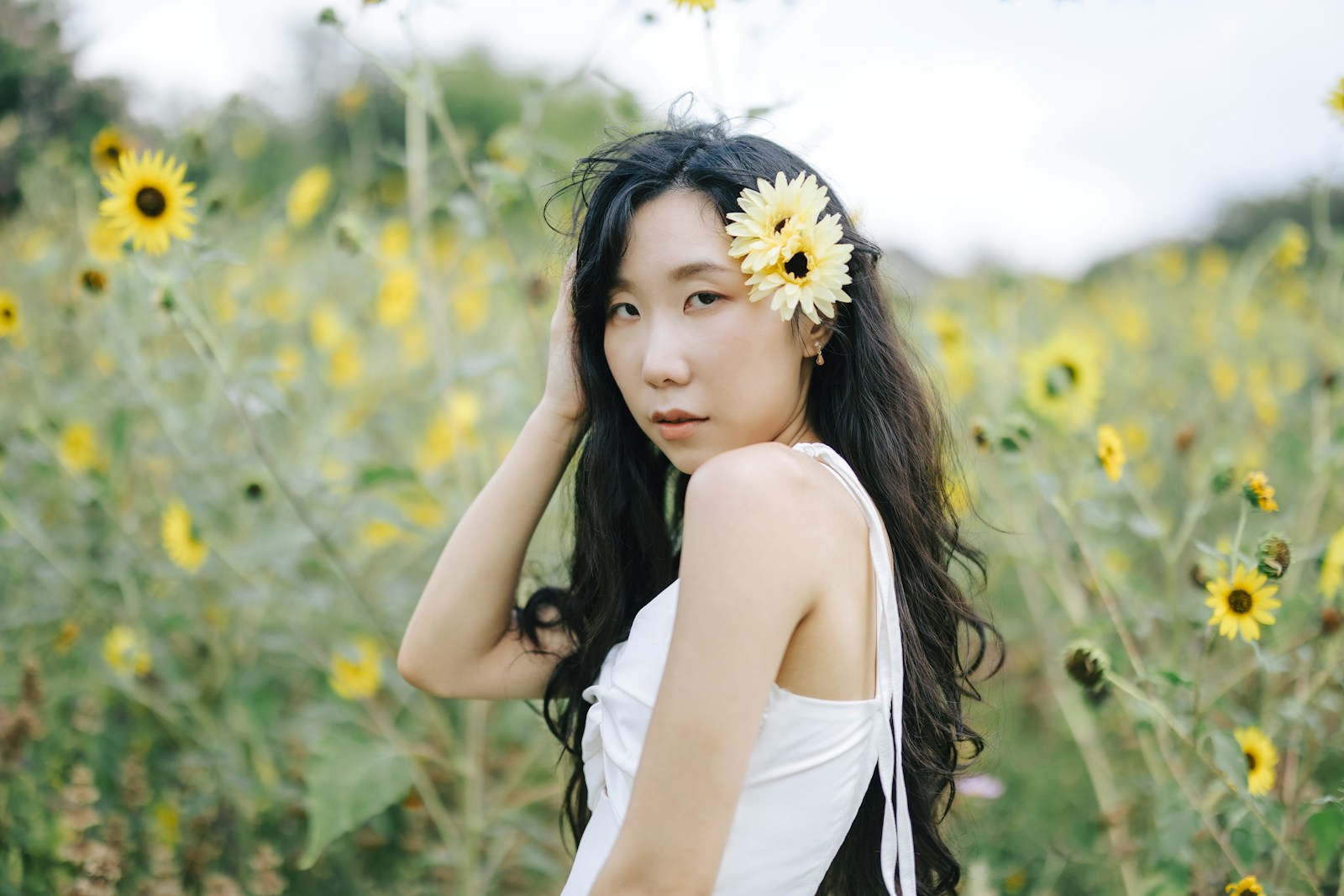 Young woman with flower in hair in sunflower field